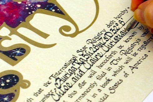 International Star Registry certificate being hand lettered with calligraphy. the certificate includes the star name, coordinates, and the date of dedication