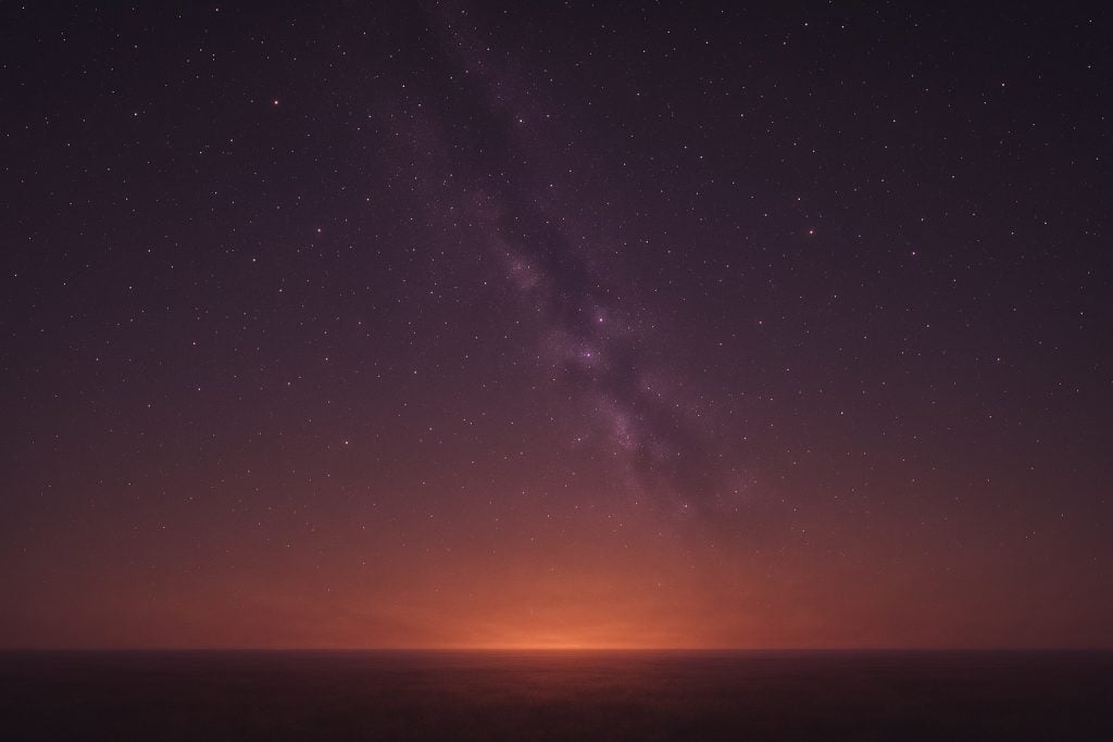 Beautiful Autumn colors cross a starry sky. We are looking toward the light on the horizon