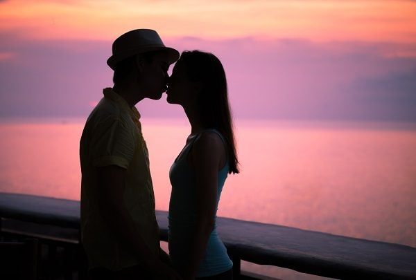 Couple kissing at the sunset over the ocean.